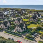 Dorf mit strohgedeckten Häusern und Blick auf das Meer