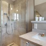 Dusche mit Glaswand und Waschbecken mit Spiegel