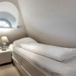 Schlafzimmer mit Bett, Nachttisch und Bogenfenster.