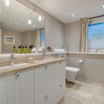 Badezimmer mit Waschbecken, Spiegel und Fenster
