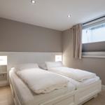 Schlafzimmer mit Doppelbett, Fenster und Nachttischen.