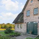 Haus mit strohgedecktem Dach und grünen Türen