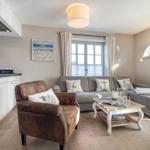 Wohnbereich mit Sofa, Sessel und Küchenzeile