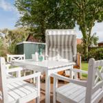 Weiße Terrassenmöbel mit Sonnenschutz und Tisch im Garten.