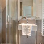 Dusche mit Duschbrause, Waschbecken und Heizkörper