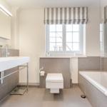 Badezimmer mit Badewanne, WC und Waschbecken unter Fenster