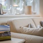 Ein Sofa mit Kissen und eine Tischlampe mit Willkommenskarte.