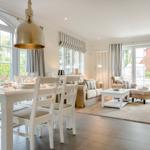 Esszimmer und Wohnbereich mit Tisch, Stühlen, Sofa und Glasfronten.