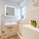 Bathroom with sink, mirror, window, and towels.