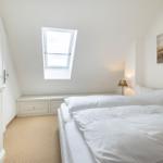 Bedroom with skylight, bed, and cabinet. Wall art with seashells.