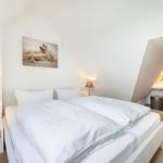 Bedroom with double bed, two nightstands, and wall art with shells.