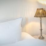 Bed headboard with pillow and nightstand with lamp.