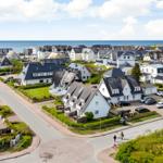 Houses with dark roofs and green gardens near the coast.