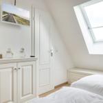 Bedroom with sloped ceiling, skylight, bed, and cabinet. TV mounted on wall.