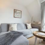 Living room with gray sofa, wooden table, and window to terrace.