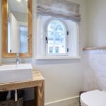 Badezimmer mit Waschtisch, Spiegel und Fenster