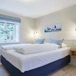 Schlafzimmer mit Bett, Fenster und Wandbild.