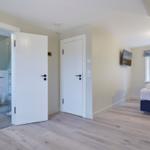 Schlafzimmer mit Doppelbett, Fenster und Tür zum Badezimmer mit Dusche.