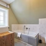 Badezimmer mit Badewanne, Fenster und Toilette.