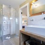 Badezimmer mit Dusche, Waschbecken und Spiegel