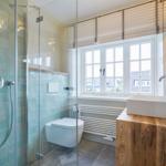 Badezimmer mit Dusche, Toilette und Waschtisch aus Holz.