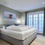 Schlafzimmer mit Doppelbett, Fenster und Wandbild.