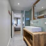 Badezimmer mit Waschbecken, Dusche und Blick in Schlafzimmer
