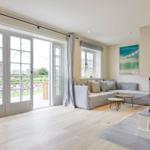 Wohnzimmer mit Kamin, Sofa und Fenster zur Terrasse.