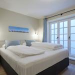 Schlafzimmer mit Doppelbett, Fenster und Wandbild.