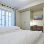 Schlafzimmer mit Doppelbett, Fenster und Schreibtisch
