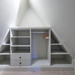 Ein weißer Schrank mit Regalen und Kleiderstange unter einem Dach