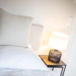 Bettkopfteil mit Kissen, Nachttisch und Lampe neben Tür
