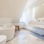 Badezimmer mit freistehender Badewanne, Waschbecken und Toilette unter schräger Decke.