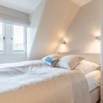 Schlafzimmer mit Dachschrägen, Fenster und Bett.