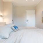 Schlafzimmer mit Bett, Wandlampe und Fernseher an der Wand.