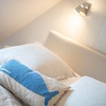 Schlafzimmer mit Bett, Kissen und Wandlampe.