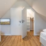 Zimmer mit zwei Betten, TV und Kleiderschrank. Holzboden und schräge Decke.