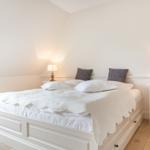 Bedroom with white bed, two nightstands, and lamps.