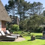 House with thatched roof, garden with loungers and pavilion.
