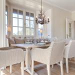 Dining room with table, chairs, and windows. Ceiling light and wooden floor.