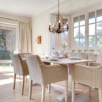Dining room with table, chairs, and windows. Chandelier and wooden floor.