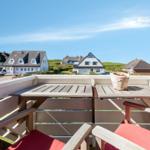 Terrasse mit Tisch und Stühlen, Blick auf Häuser und grüne Hügel.