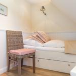 Schlafzimmer mit Bett, Stuhl und Wandlampe unter Dachschräge