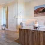 Wohnzimmer mit Sofa, Holztisch und Wandbild. Treppenhaus und Tür im Hintergrund.