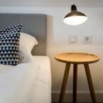Bedroom with bed, nightstand, and wall lamp.