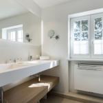 Bathroom with sink, mirror, and window with view of trees.