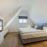 Bedroom with sloped ceiling, bed, window, and TV.