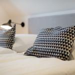 A bed with pillows and a wall lamp