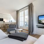 Living area with sofa, TV, and view of balcony.