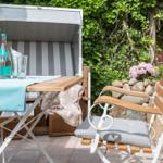 Outdoor area with beach chair, table, and chair. Background: green plants and stone wall.